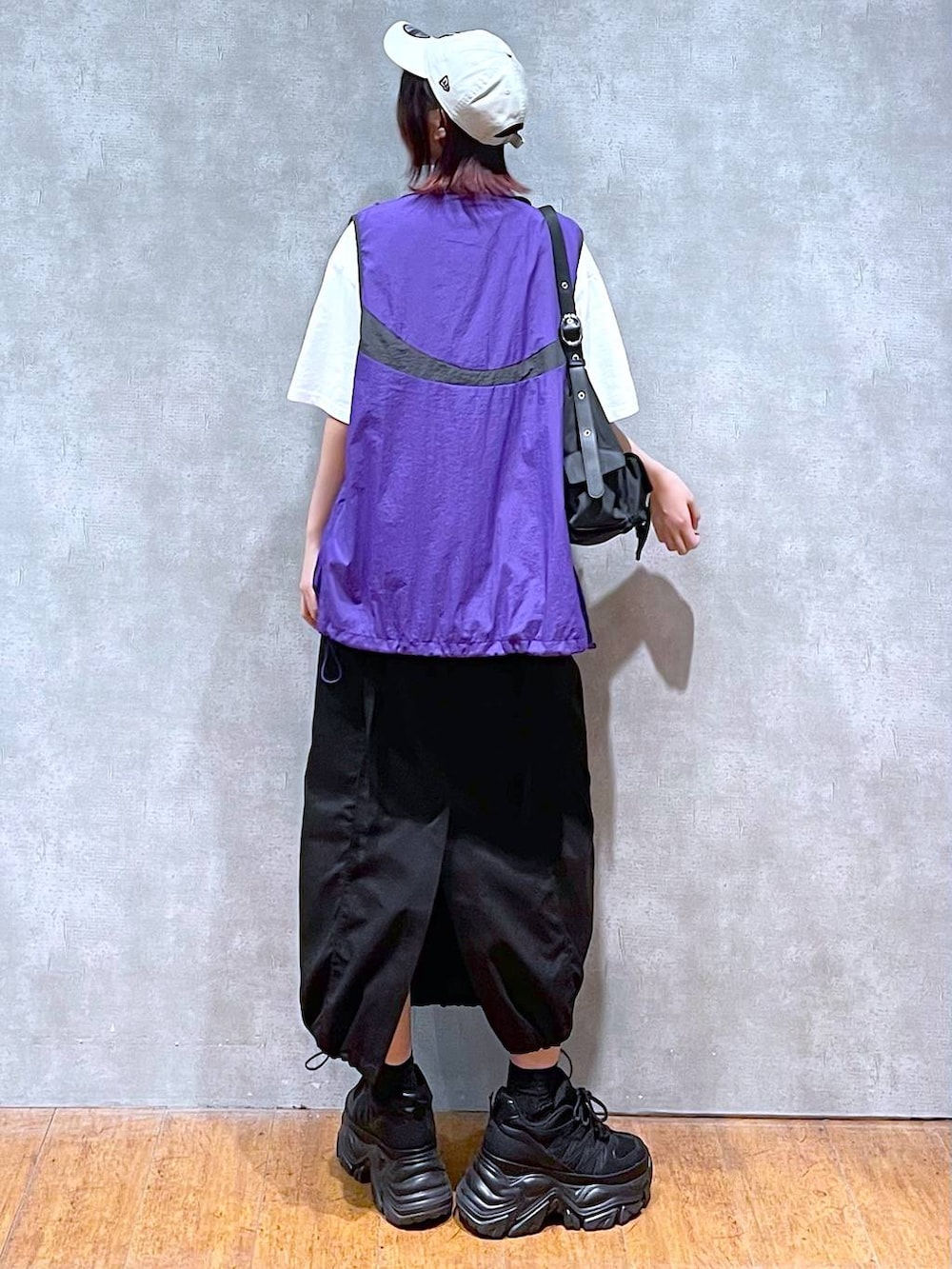 ブラック系のショルダーバッグ、ブラック系のスニーカー、パープル系のベストを着用したレディースの春コーディネートの6枚目の写真