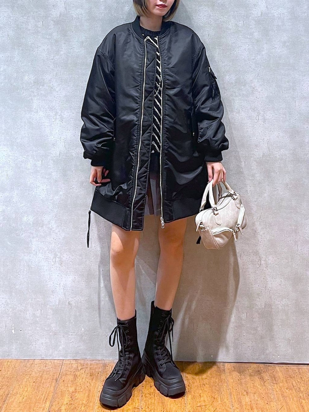 ブラック系のMA-1、ブラック系のブーツ、ブラック系のニット/セーターを着用したレディースの冬コーディネートの2枚目の写真