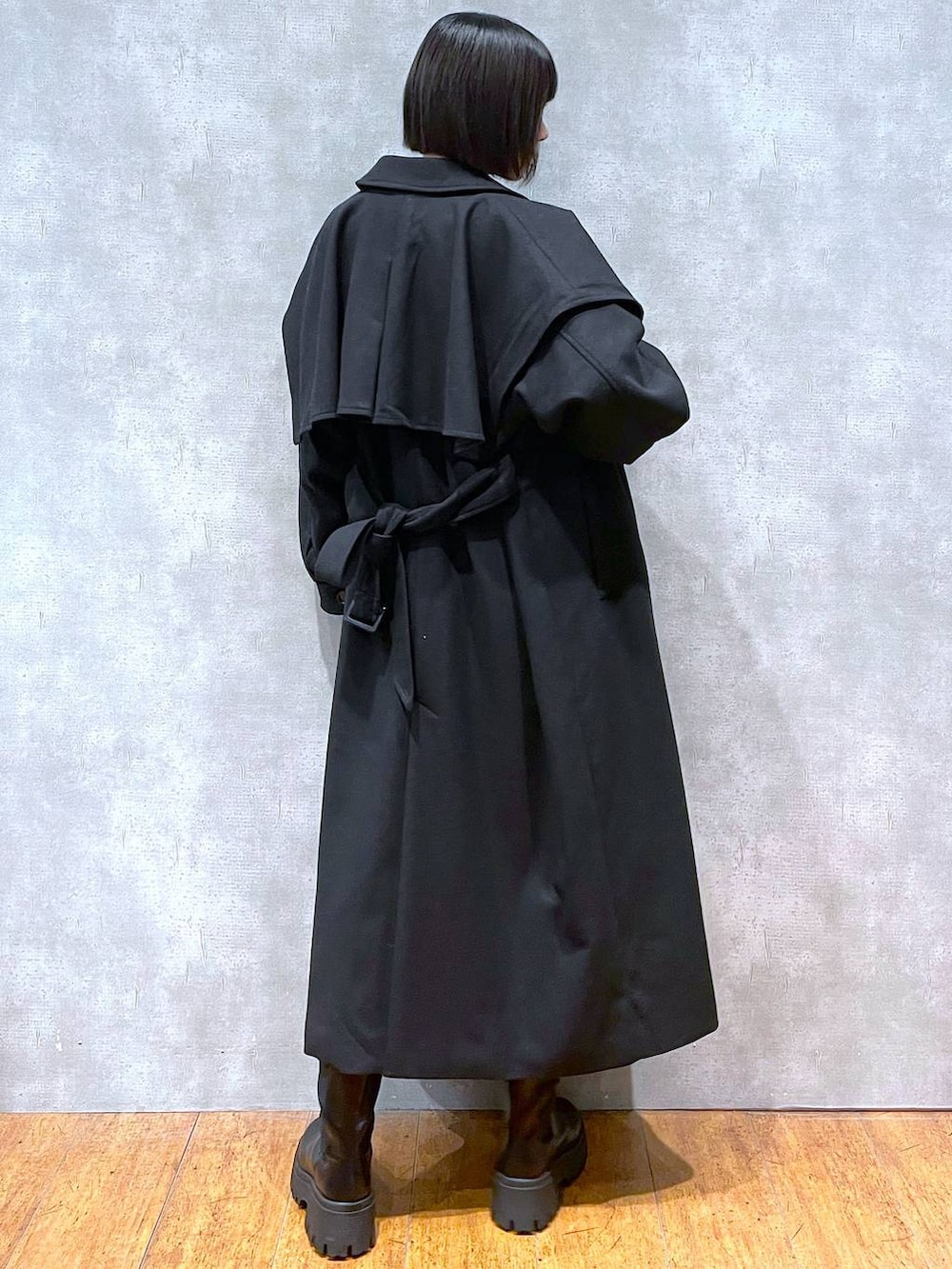 ブラック系のチェスターコート、ブラック系のブーツ、ブラック系のニット/セーターを着用したレディースの冬コーディネートの4枚目の写真