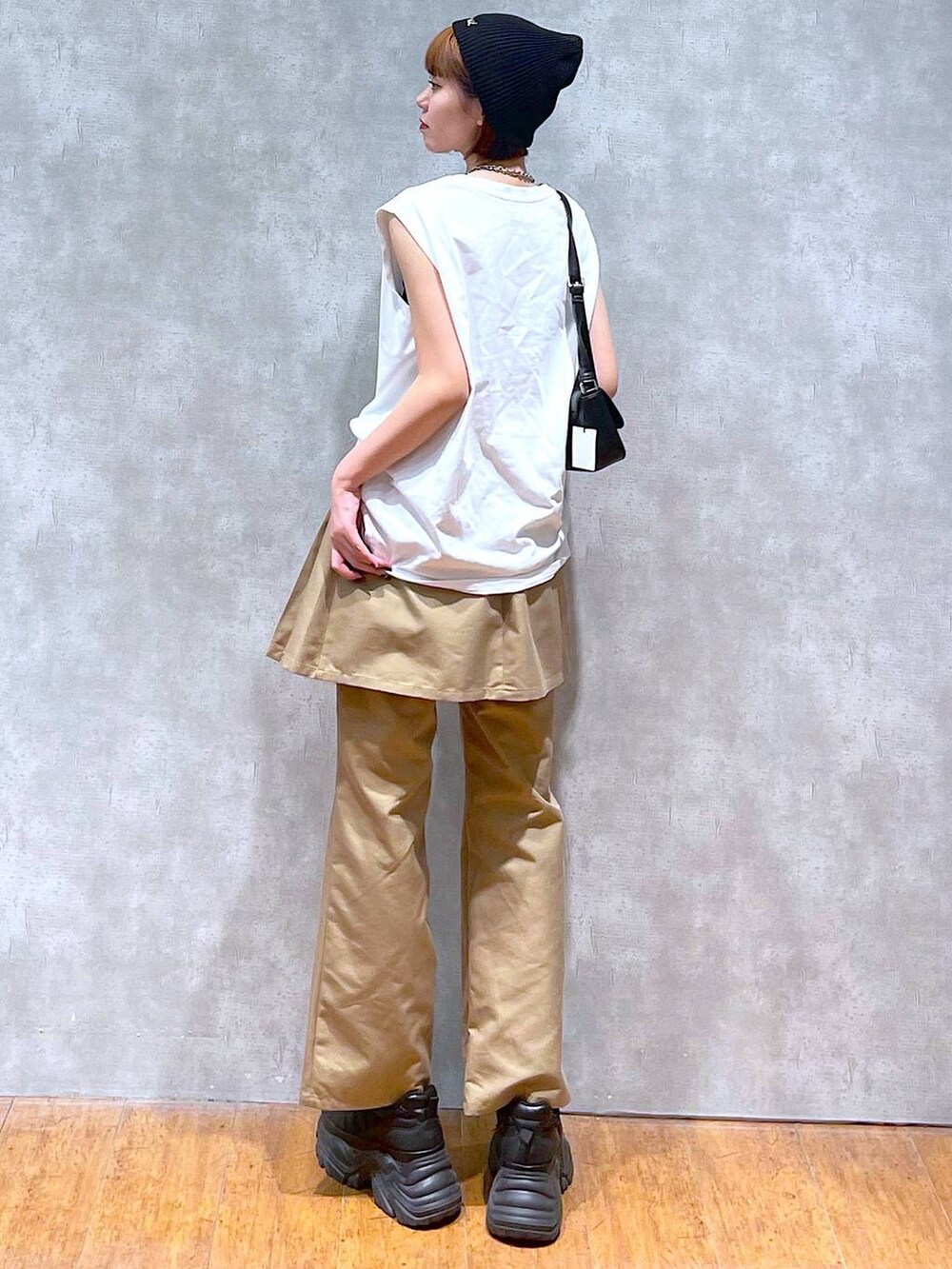 ブラック系のスニーカー、ブラック系のハンドバッグ、ホワイト系のTシャツ/カットソーを着用したレディースの夏コーディネートの5枚目の写真