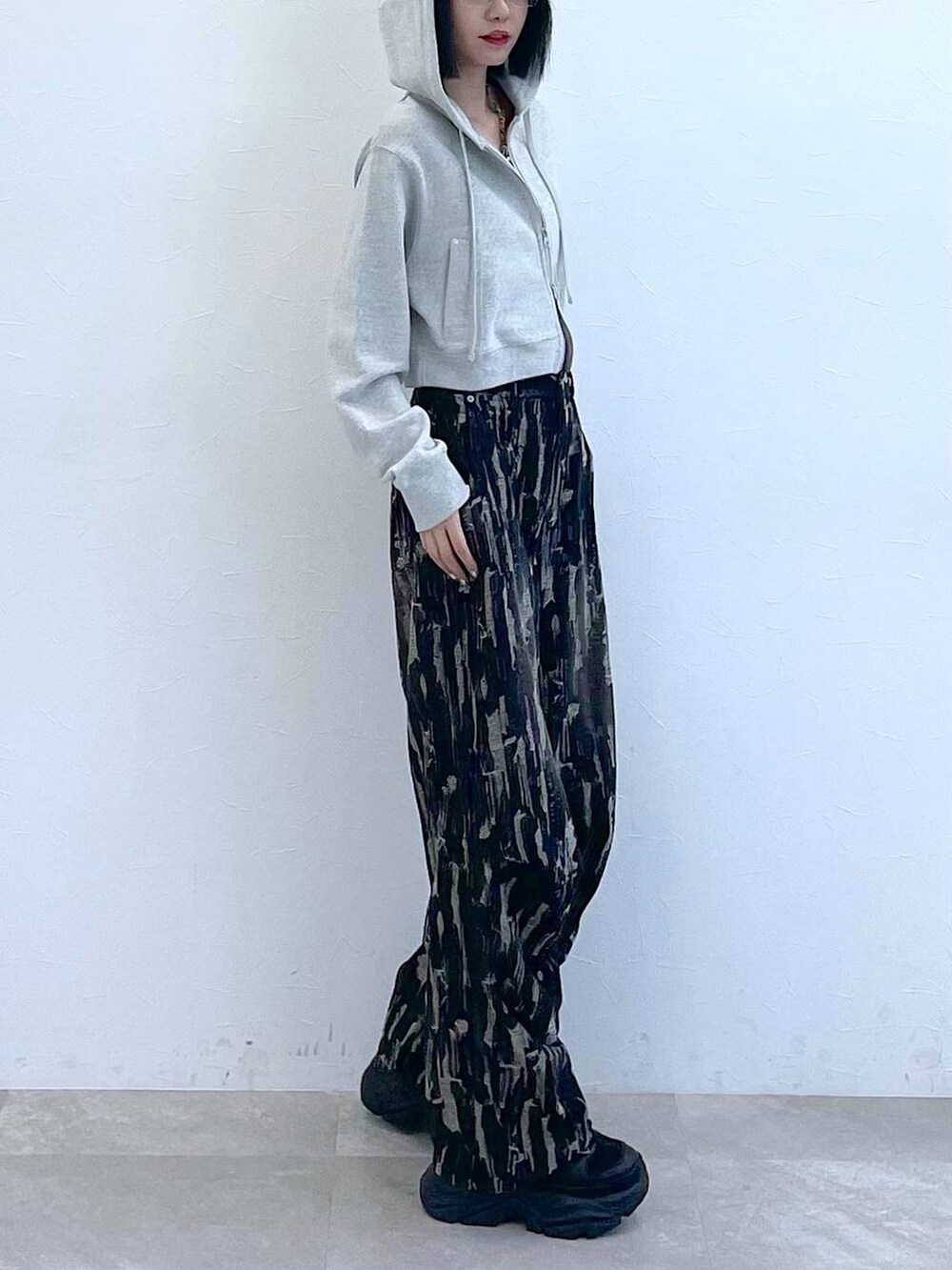 グレー系のパーカー、ホワイト系のキャミソール、ブラック系のスニーカーを着用したレディースの秋コーディネートの5枚目の写真