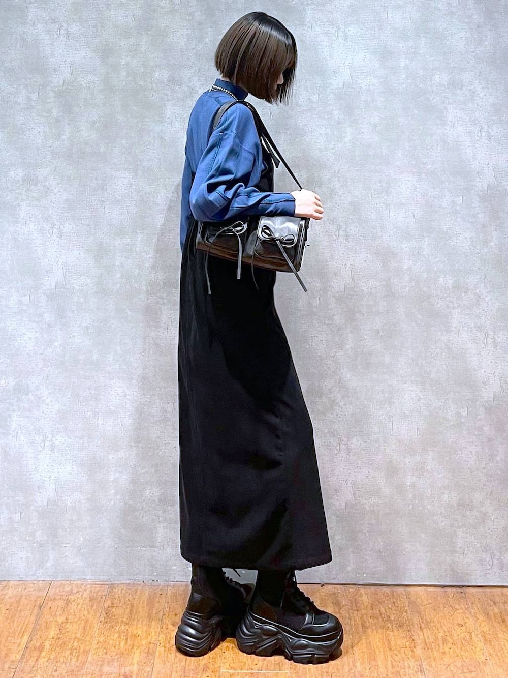 ブラック系のショルダーバッグ、ブラック系のブーツ、ブルー系のニット/セーターを着用したレディースの秋コーディネートの3枚目の写真