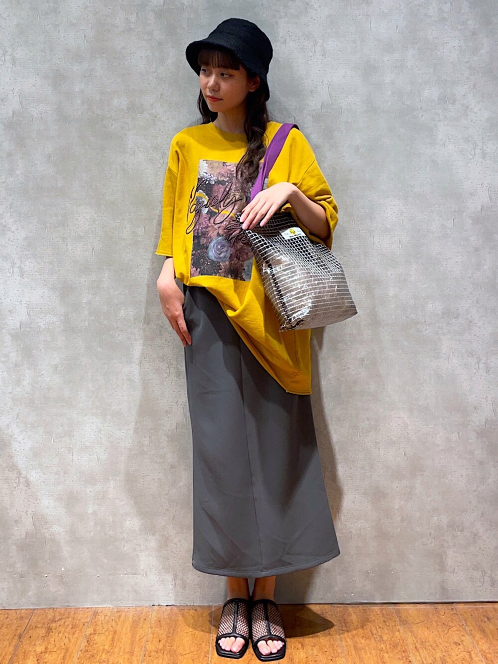 イエロー系のTシャツ/カットソー、グリーン系のトートバッグ、グレー系のスカートを着用したレディースの夏コーディネートの3枚目の写真