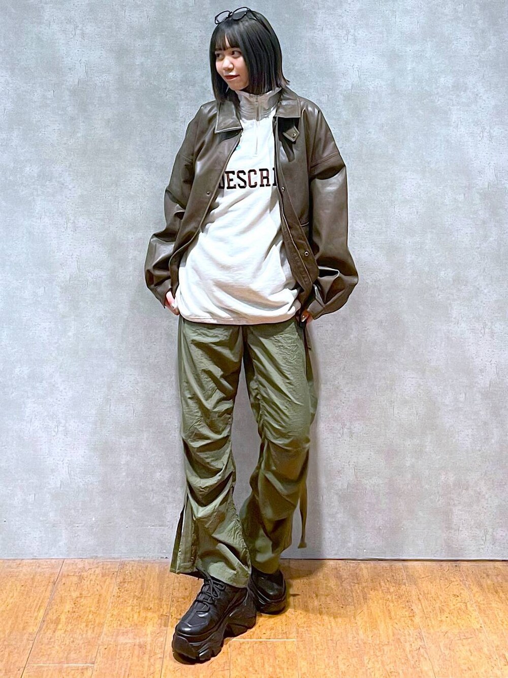 ブラック系のスニーカー、グリーン系のカーゴパンツ、ブラウン系のブルゾンを着用したレディースの秋コーディネートの2枚目の写真