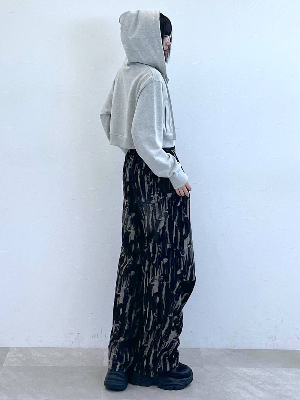 グレー系のパーカー、ホワイト系のキャミソール、ブラック系のスニーカーを着用したレディースの秋コーディネートの2枚目の写真