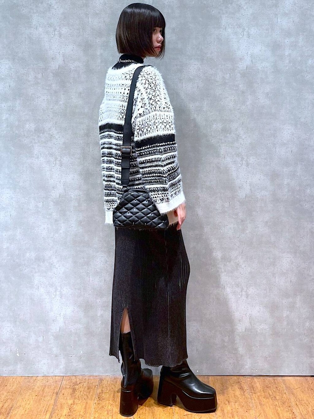 ブラック系のニット/セーター、ブラック系のブーツ、ブラック系のショルダーバッグを着用したレディースの冬コーディネートの2枚目の写真