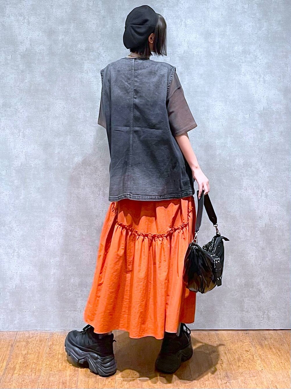 ブラック系のスニーカー、ブラック系のショルダーバッグ、オレンジ系のスカートを着用したレディースの夏コーディネートの5枚目の写真
