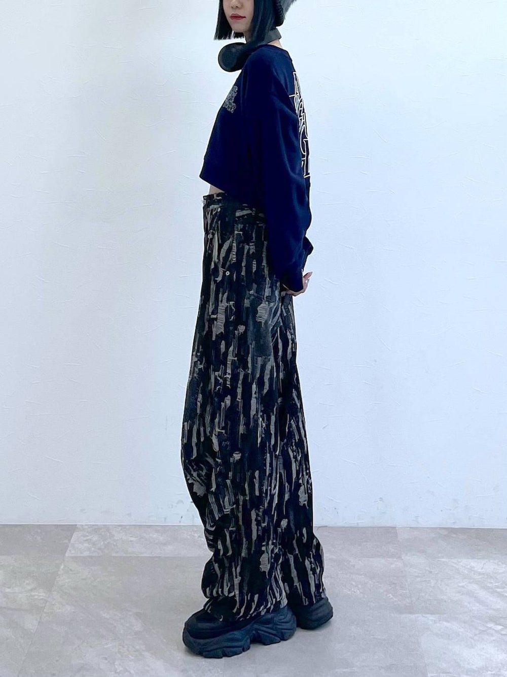 ブラック系のスニーカー、ブラック系のデニムパンツ、ホワイト系のキャミソールを着用したレディースの秋コーディネートの6枚目の写真