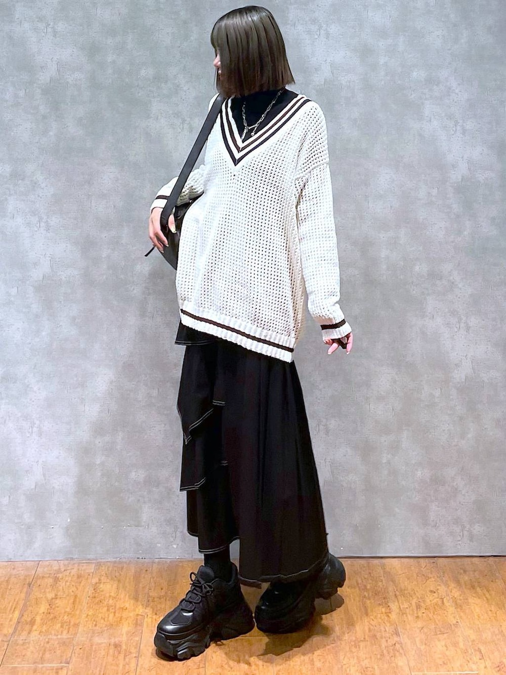 ブラック系のスニーカー、ブラック系のニット/セーター、ブラック系のショルダーバッグを着用したレディースの秋コーディネートの6枚目の写真