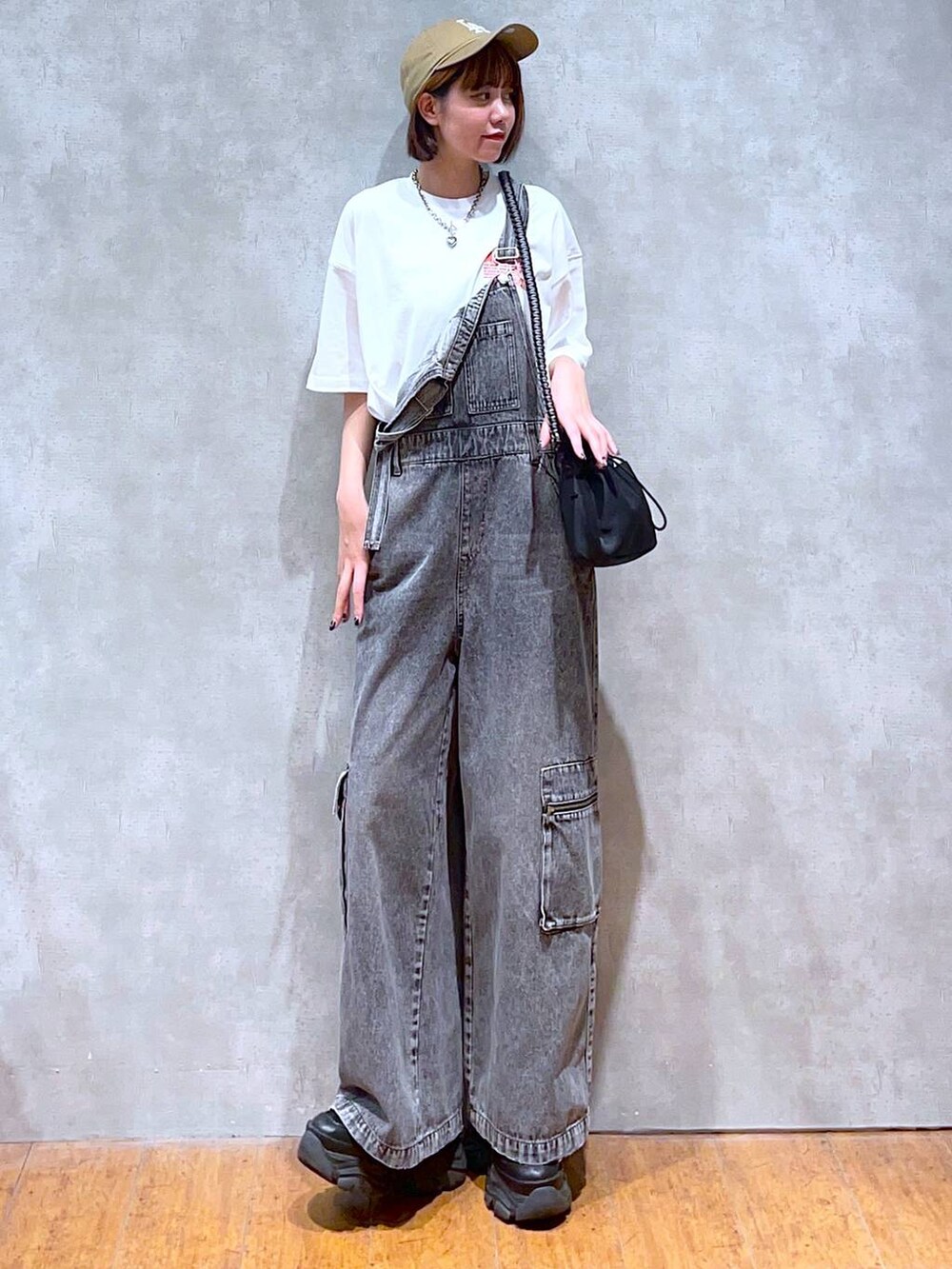 ブラック系のスニーカー、ブラック系のショルダーバッグ、ホワイト系のTシャツ/カットソーを着用したレディースの夏コーディネートの3枚目の写真