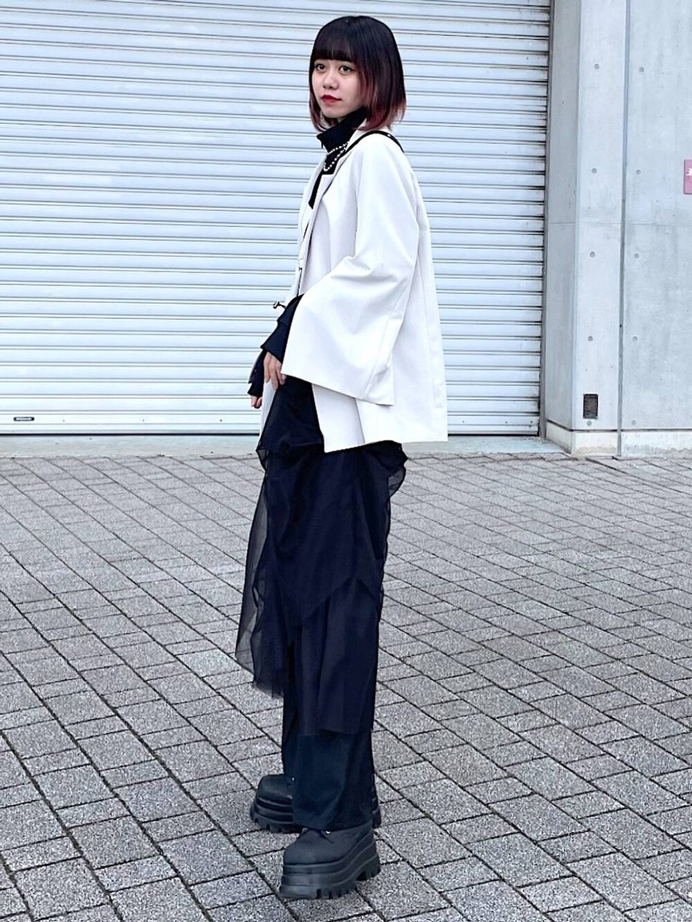 ブラック系のショルダーバッグ、ブラック系のナイロンジャケット、ブラック系のスカートを着用したレディースの春コーディネートの6枚目の写真