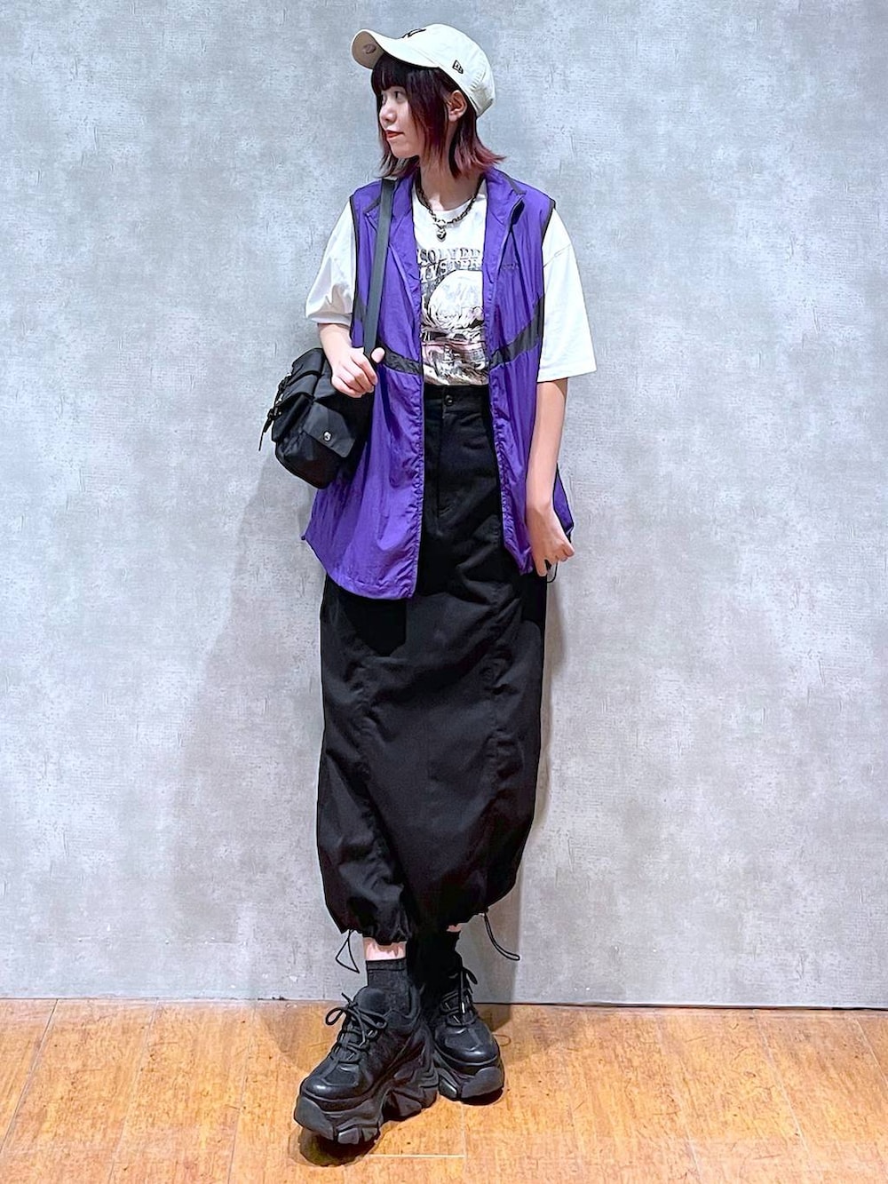 ブラック系のショルダーバッグ、ブラック系のスニーカー、パープル系のベストを着用したレディースの春コーディネートの3枚目の写真