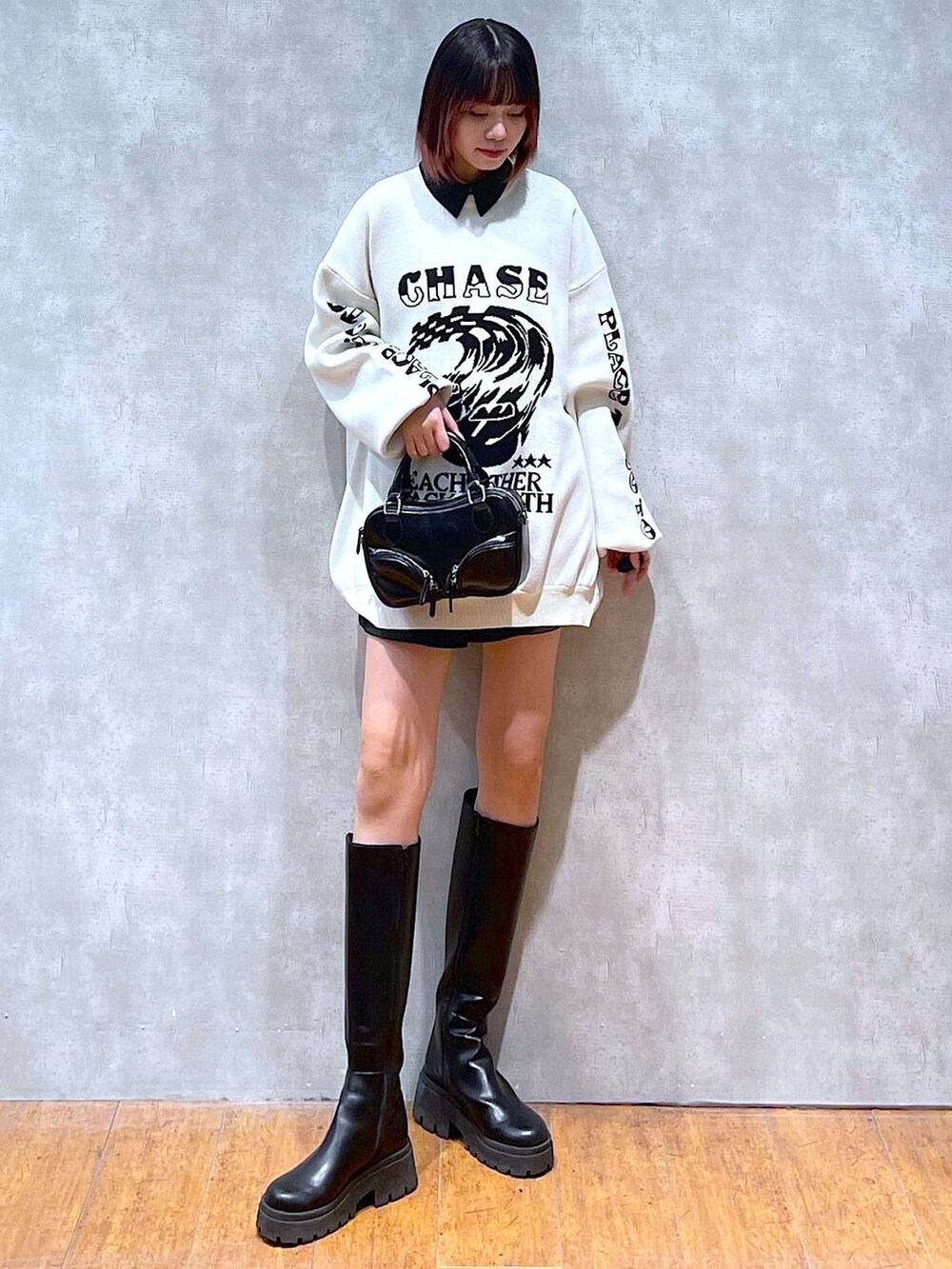 ブラック系のシャツ/ブラウス、ホワイト系のニット/セーター、ブラック系のブーツを着用したレディースの冬コーディネートの3枚目の写真