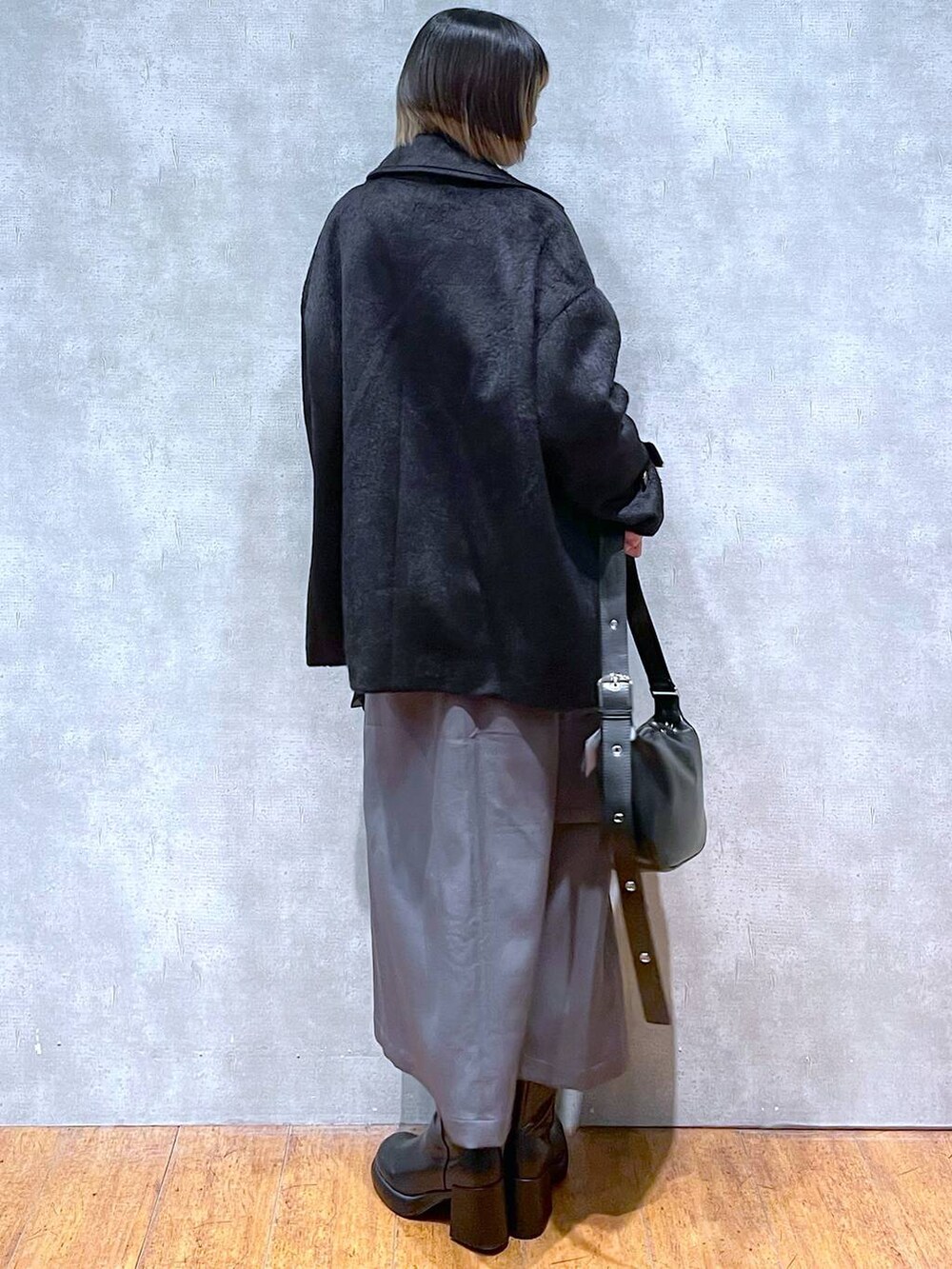 グレー系のスカート、ブラック系のスウェット、ブラック系のショルダーバッグを着用したレディースの冬コーディネートの3枚目の写真