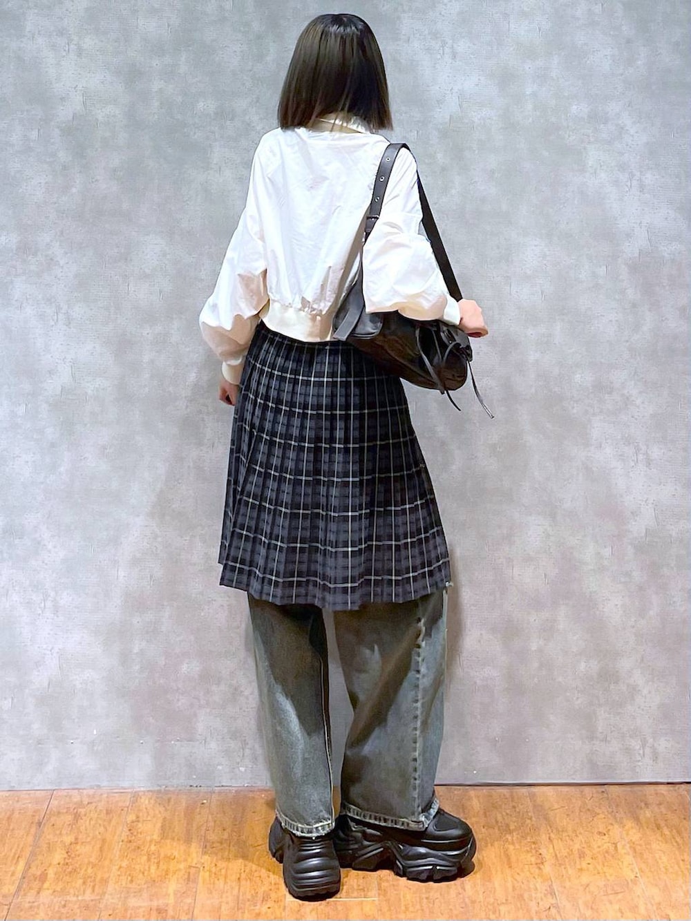 ブラック系のスニーカー、ブラック系のショルダーバッグ、ブルー系のデニムパンツを着用したレディースの秋コーディネートの4枚目の写真