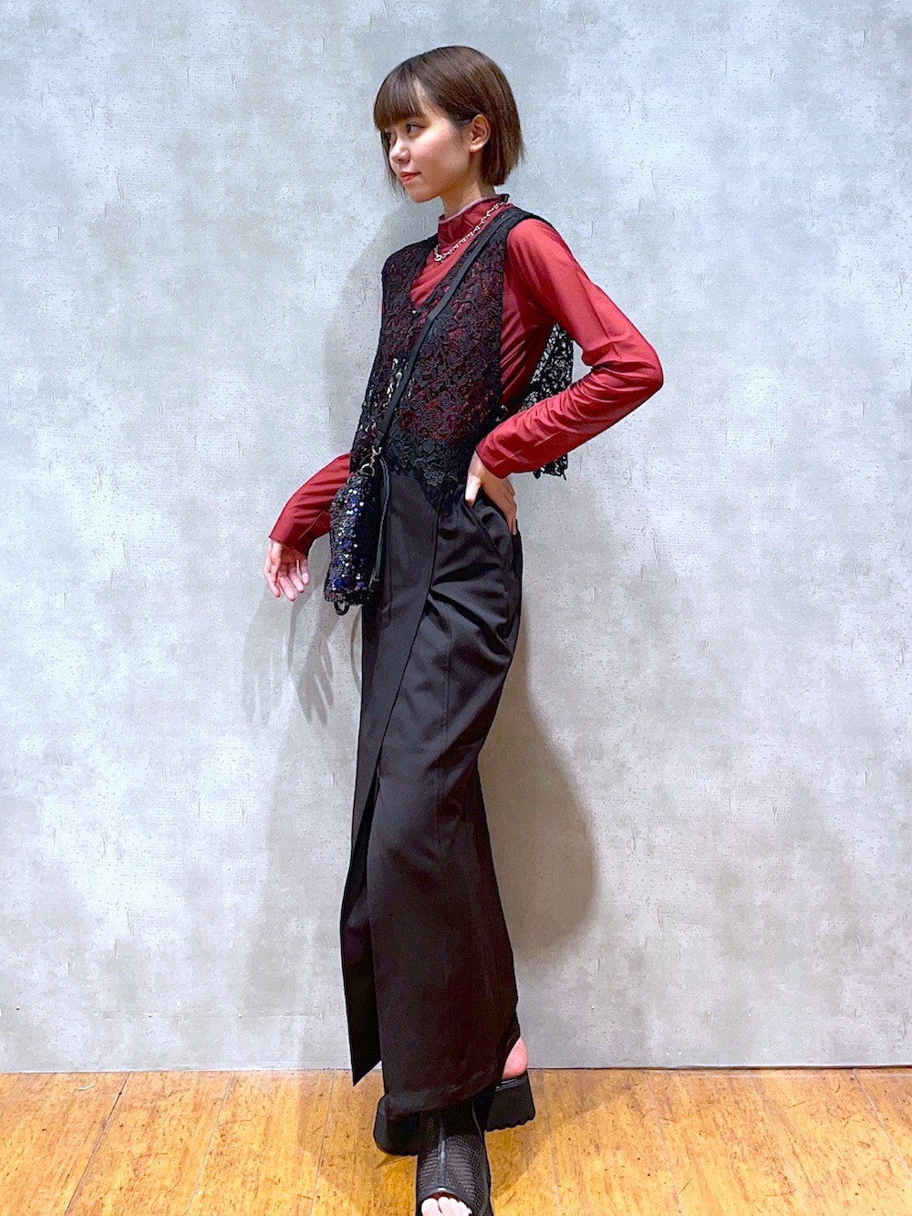 ブラック系のベスト、レッド系のTシャツ/カットソー、ブラック系のショルダーバッグを着用したレディースの夏コーディネートの2枚目の写真