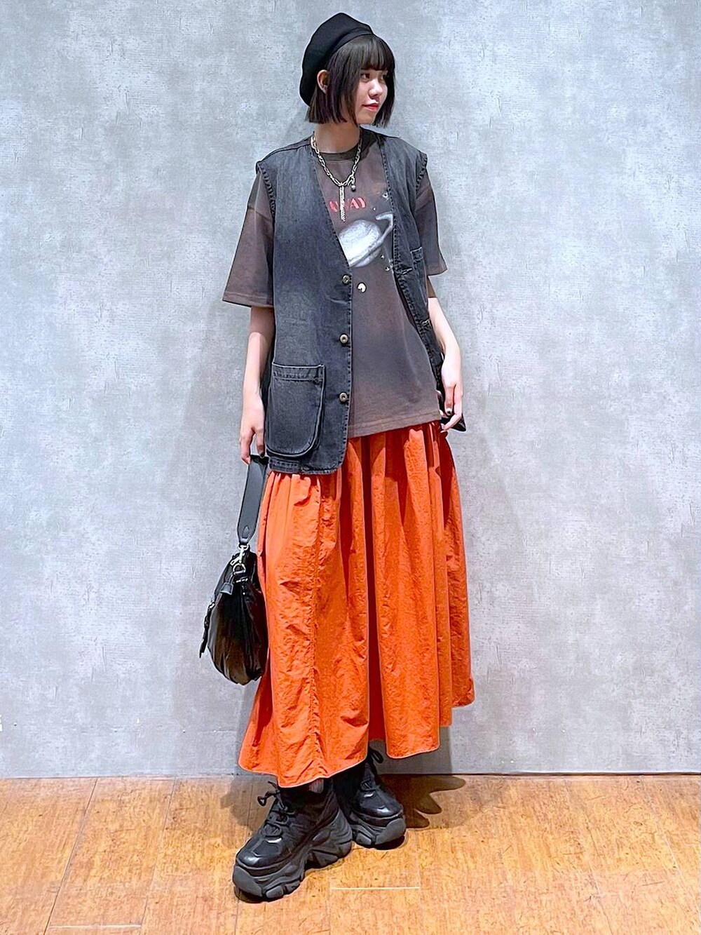 ブラック系のスニーカー、ブラック系のショルダーバッグ、オレンジ系のスカートを着用したレディースの夏コーディネートの7枚目の写真