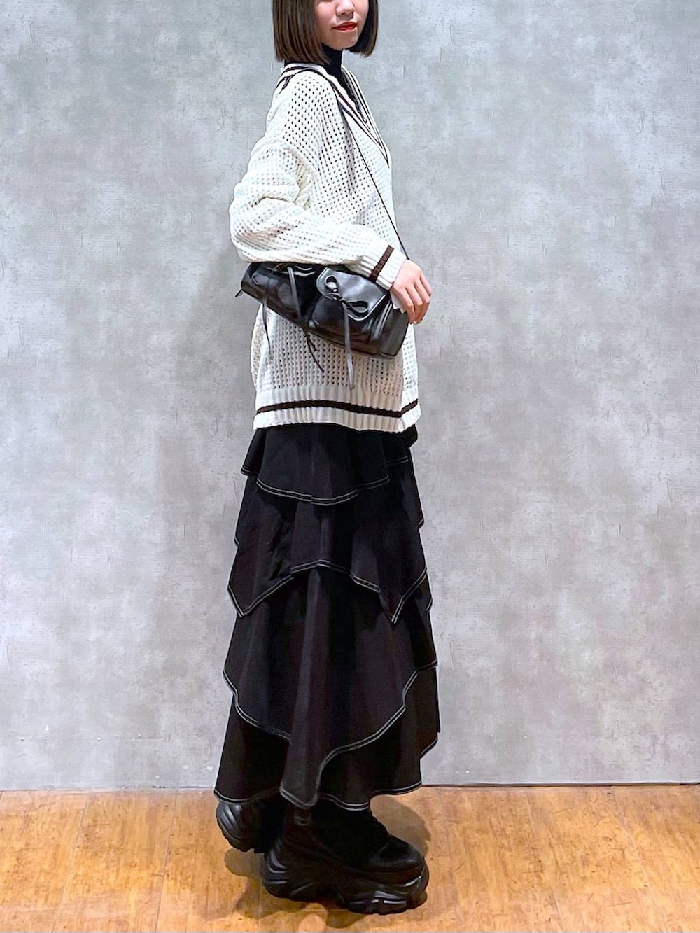 ブラック系のスニーカー、ブラック系のニット/セーター、ブラック系のショルダーバッグを着用したレディースの秋コーディネートの3枚目の写真