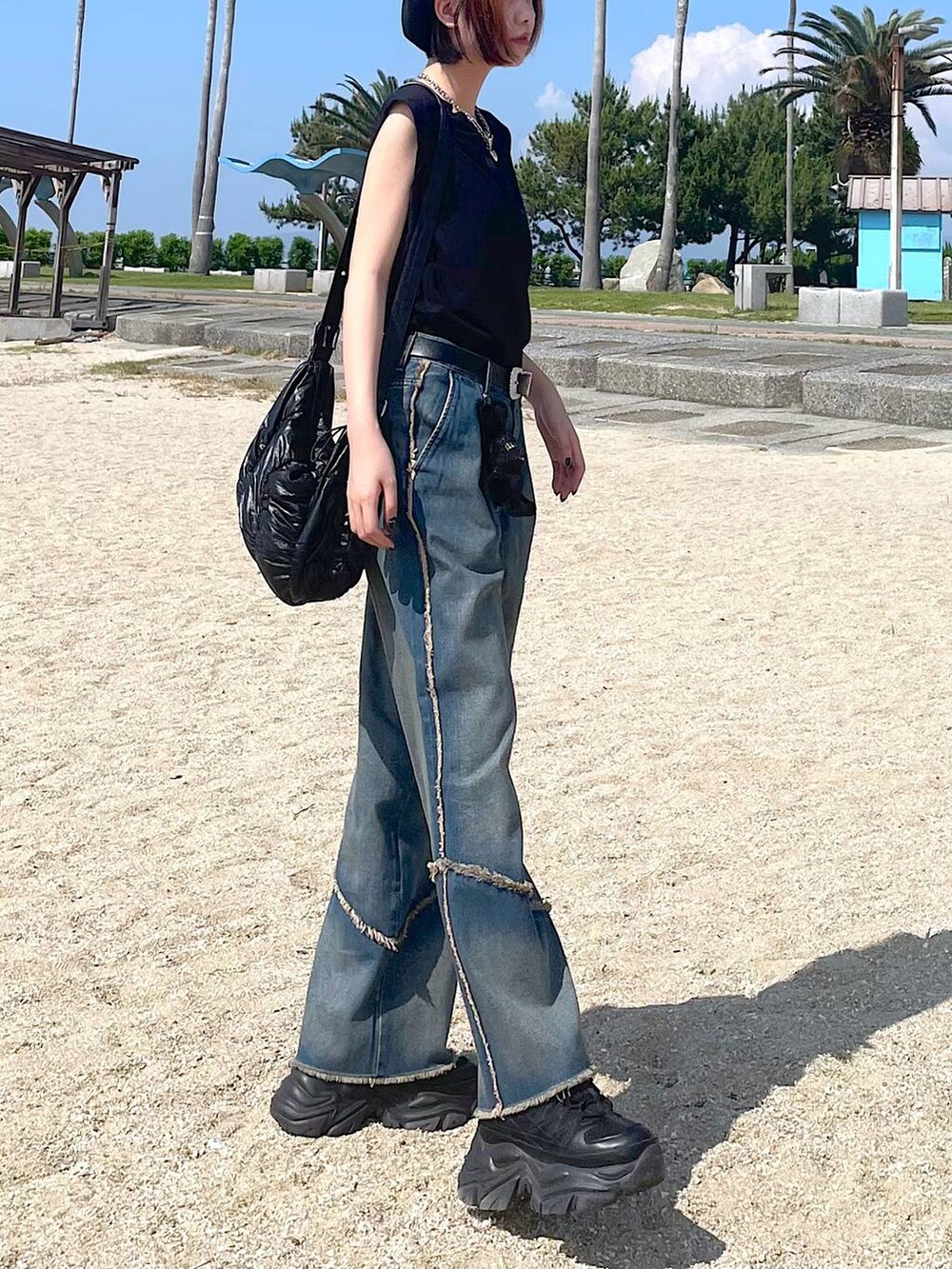 ブラック系のショルダーバッグ、ブラック系のスニーカー、オレンジ系のデニムパンツを着用したレディースの夏コーディネートの5枚目の写真