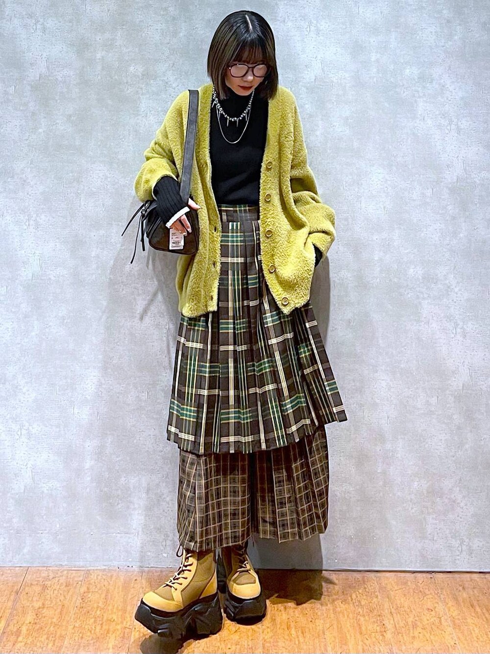 ブラック系のニット/セーター、ブラック系のショルダーバッグ、ブラウン系のブーツを着用したレディースの秋コーディネートの10枚目の写真