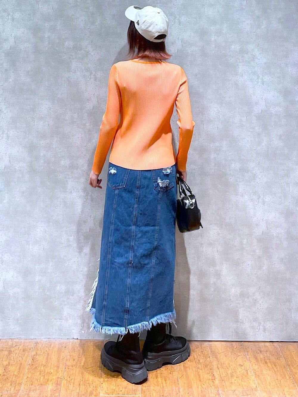 オレンジ系のニット/セーター、ブラック系のキャミソール、ブラック系のボストンバッグを着用したレディースの春コーディネートの5枚目の写真