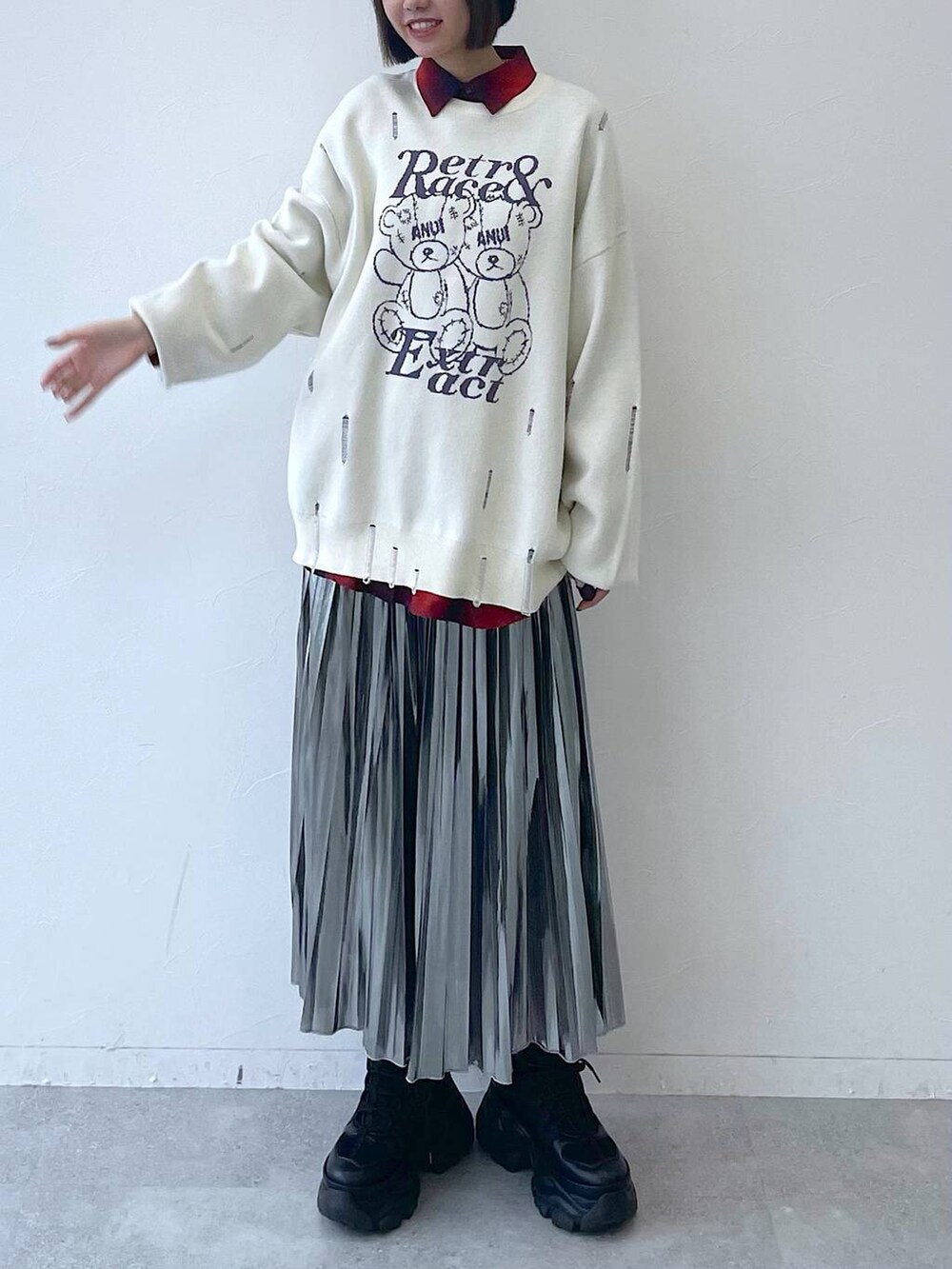 ブラック系のスニーカー、グレー系のスカート、ホワイト系のニット/セーターを着用したレディースの秋コーディネートの9枚目の写真