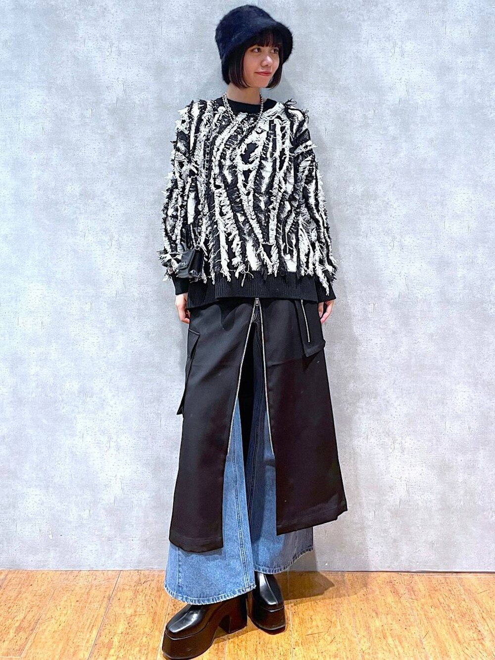 ブラック系のスカート、ブルー系のデニムパンツ、ブラック系のブーツを着用したレディースの冬コーディネートの2枚目の写真