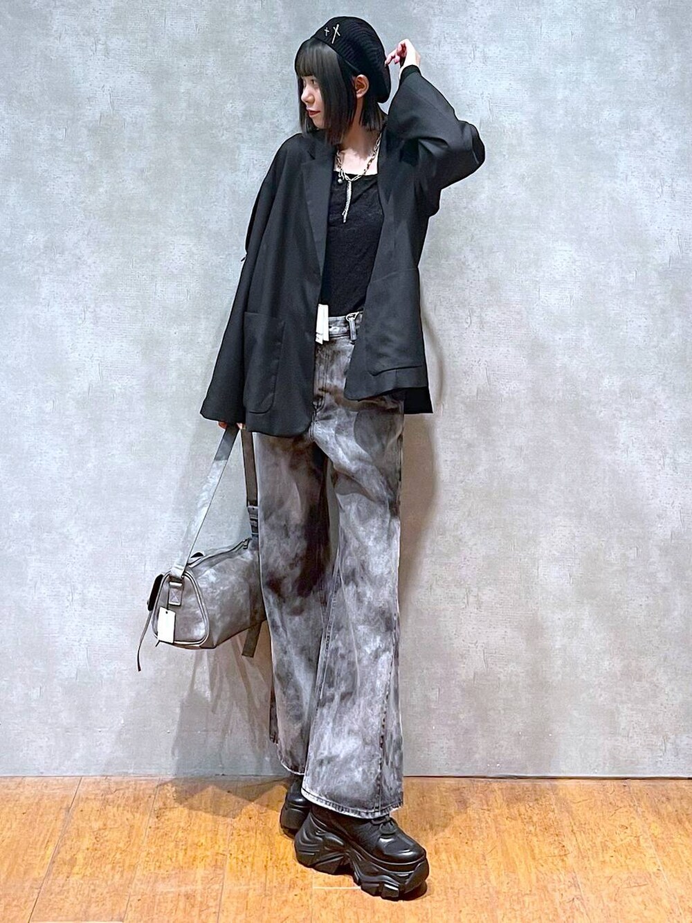 ブラック系のスニーカー、グレー系のショルダーバッグ、ブラック系のデニムパンツを着用したレディースの秋コーディネートの2枚目の写真