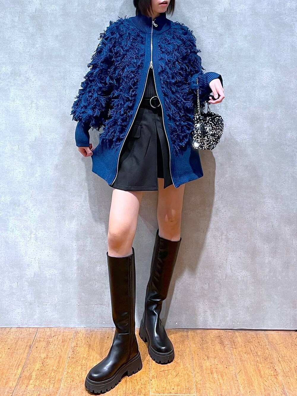 ブラック系のブーツ、ブラック系のニット/セーター、シルバー系のショルダーバッグを着用したレディースの冬コーディネートの3枚目の写真