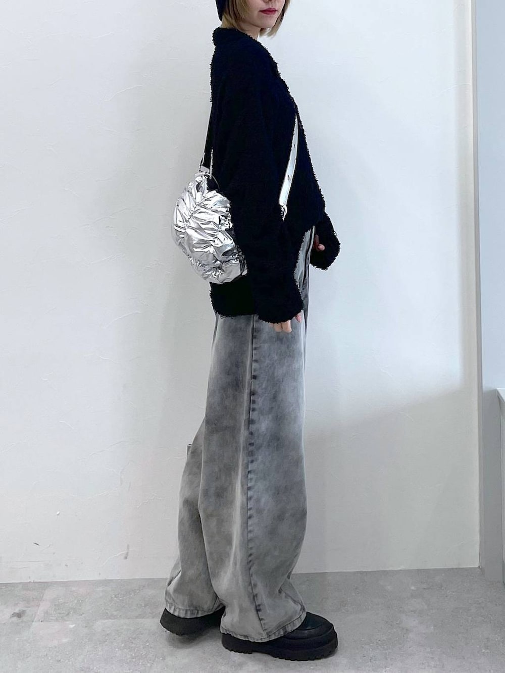 シルバー系のショルダーバッグ、ブラック系のブーツ、ブラック系のデニムパンツを着用したレディースの冬コーディネートの6枚目の写真