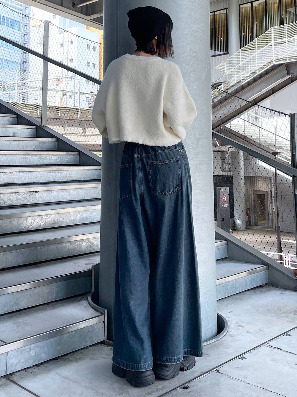 ブラック系のスニーカー、ブルー系のデニムパンツ、ホワイト系のニット/セーターを着用したレディースの秋コーディネートの5枚目の写真