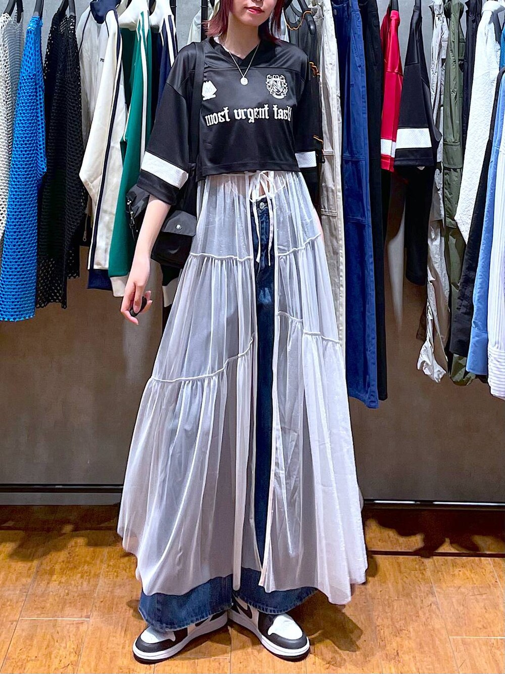 ブラック系のショルダーバッグ、ブルー系のデニムパンツ、ホワイト系のワンピースを着用したレディースの春コーディネートの2枚目の写真