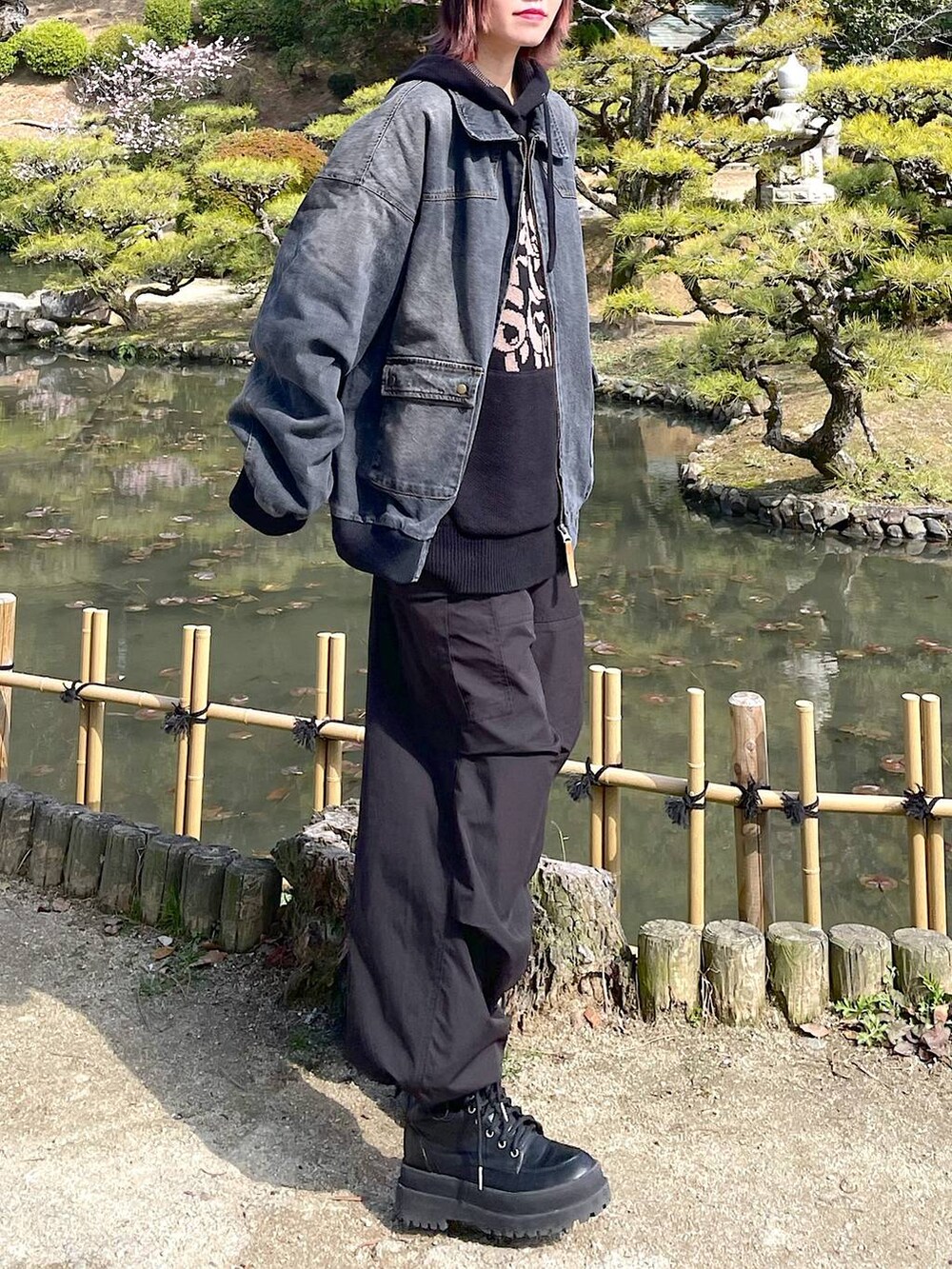 ブラック系のデニムジャケット、ブラック系のブーツ、ブラック系のスラックスを着用したレディースの春コーディネートの4枚目の写真