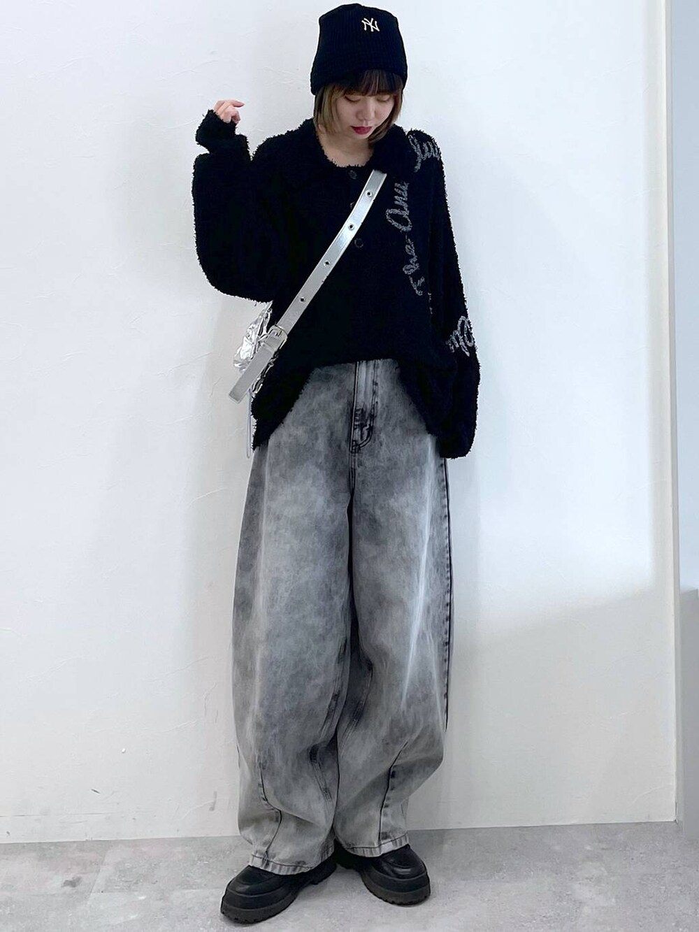 シルバー系のショルダーバッグ、ブラック系のブーツ、ブラック系のデニムパンツを着用したレディースの冬コーディネートの4枚目の写真