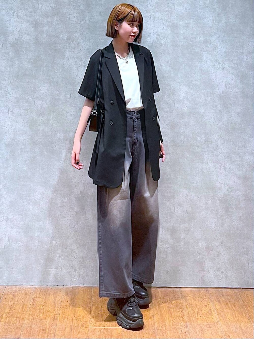 ブラック系のスニーカー、ホワイト系のTシャツ/カットソー、ブラック系のハンドバッグを着用したレディースの夏コーディネートの2枚目の写真