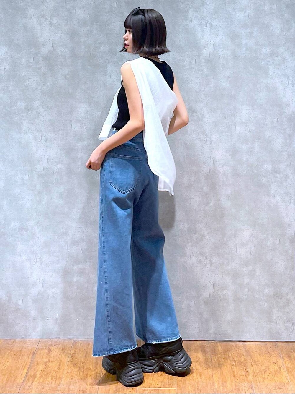 ブラック系のスニーカー、ブラック系のタンクトップ、ブルー系のデニムパンツを着用したレディースの夏コーディネートの3枚目の写真