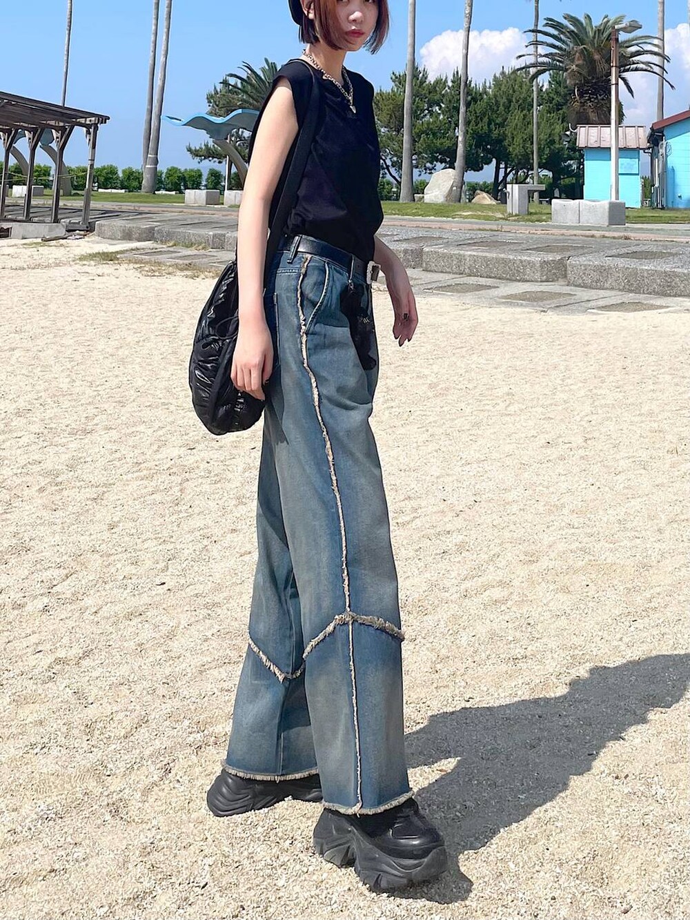 ブラック系のショルダーバッグ、ブラック系のスニーカー、オレンジ系のデニムパンツを着用したレディースの夏コーディネートの2枚目の写真