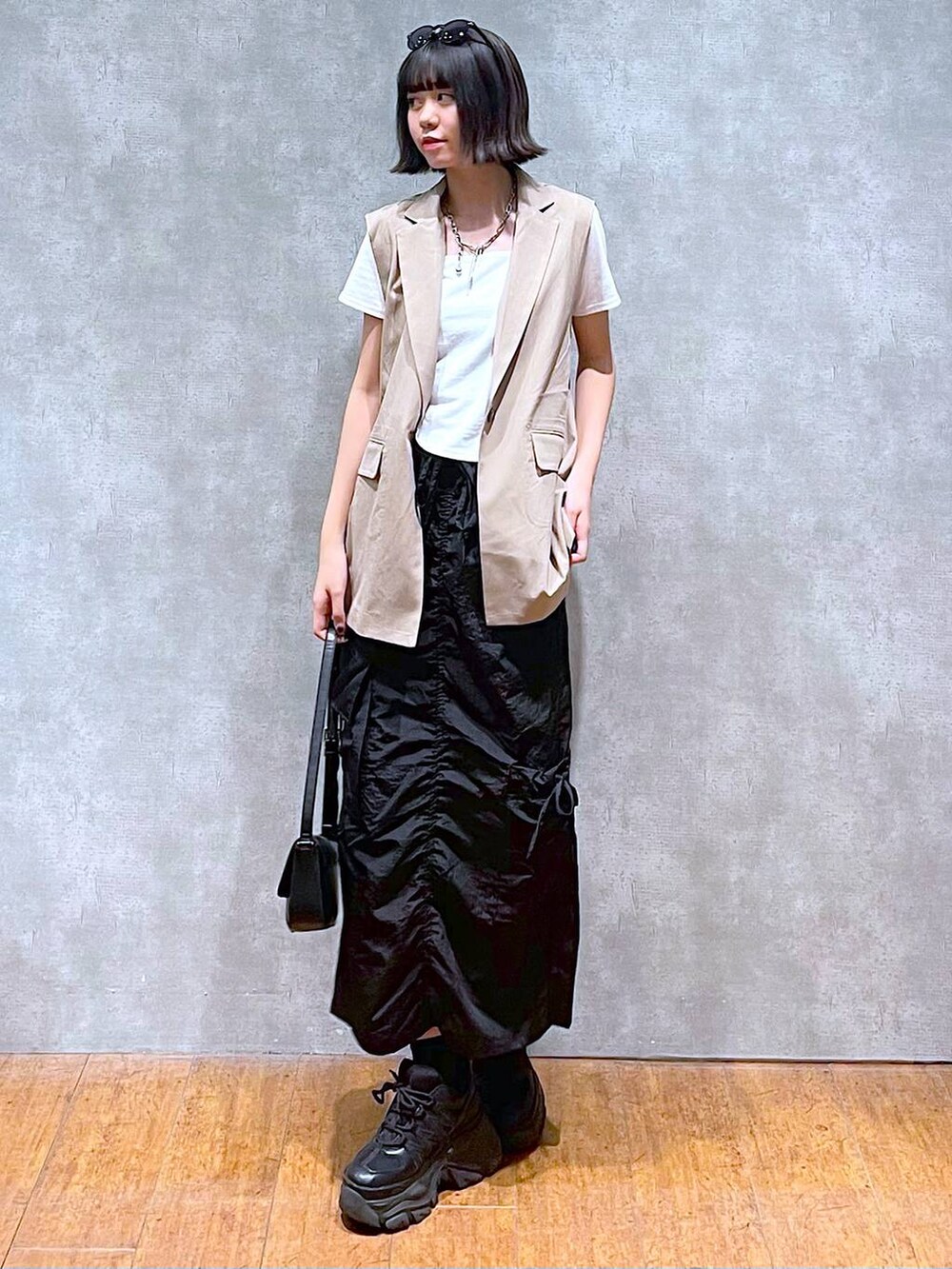 ブラック系のスニーカー、ブラック系のハンドバッグ、ホワイト系のTシャツ/カットソーを着用したレディースの夏コーディネートの4枚目の写真