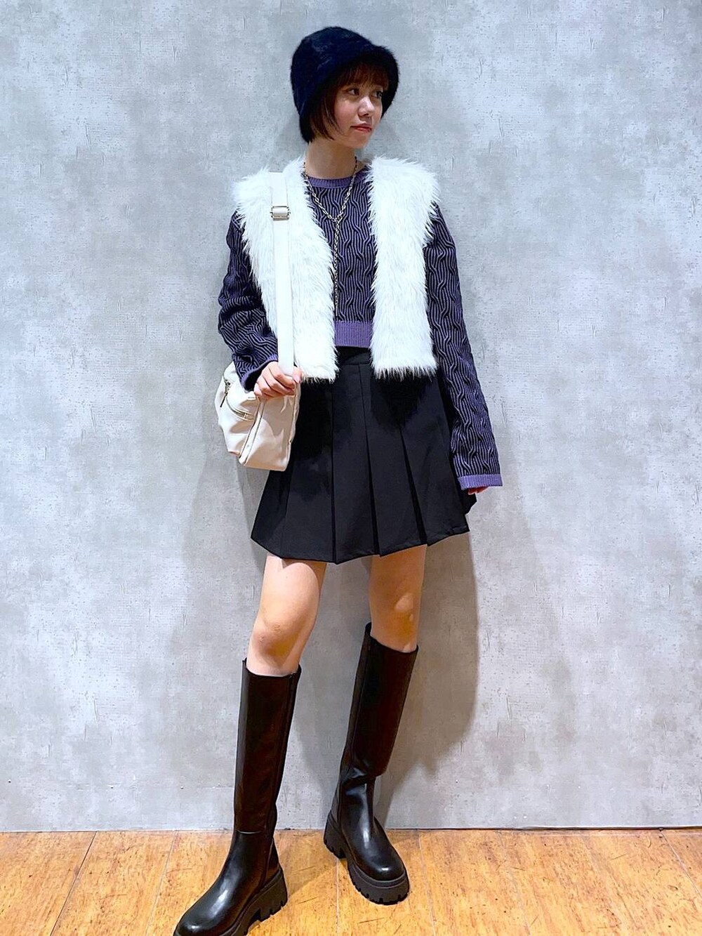 ホワイト系のショルダーバッグ、ブラック系のブーツ、ブラック系のスカートを着用したレディースの秋コーディネートの3枚目の写真