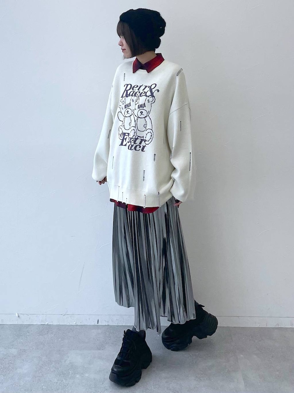 ブラック系のスニーカー、グレー系のスカート、ホワイト系のニット/セーターを着用したレディースの秋コーディネートの2枚目の写真