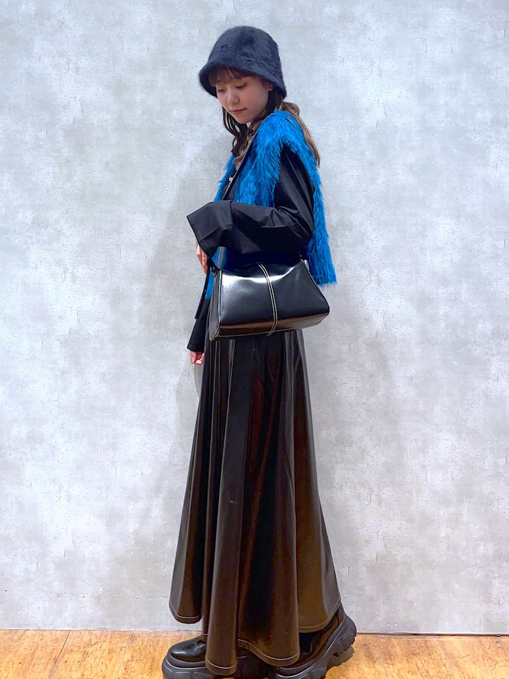 ブラック系のTシャツ/カットソー、ブルー系のベスト、ブラック系のスカートを着用したレディースの秋コーディネートの2枚目の写真