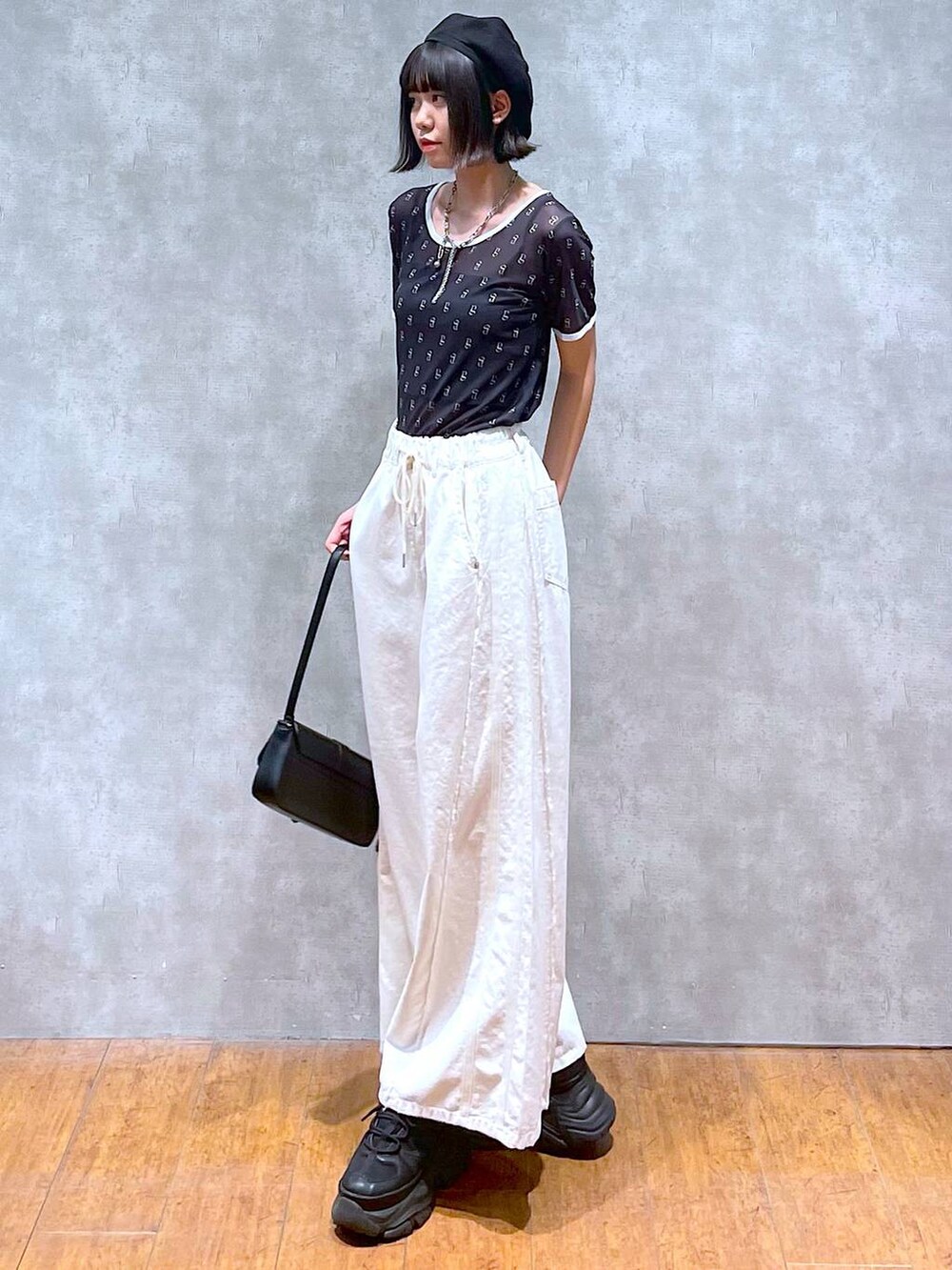 ブラック系のスニーカー、ブラック系のキャミソール、ホワイト系のデニムパンツを着用したレディースの夏コーディネートの2枚目の写真