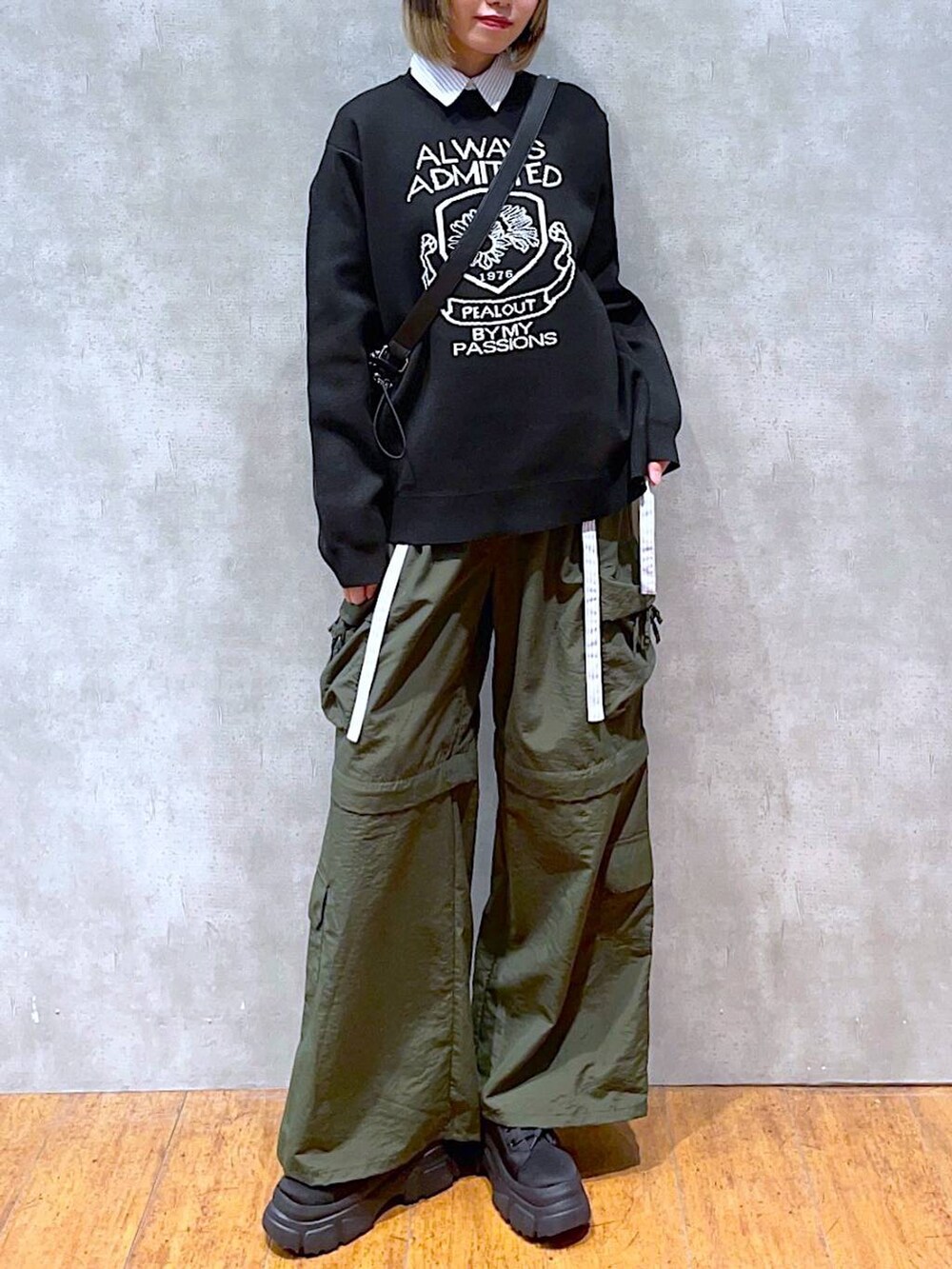 ブラック系のショルダーバッグ、ブラック系のニット/セーター、ブルー系のシャツ/ブラウスを着用したレディースの冬コーディネートの3枚目の写真