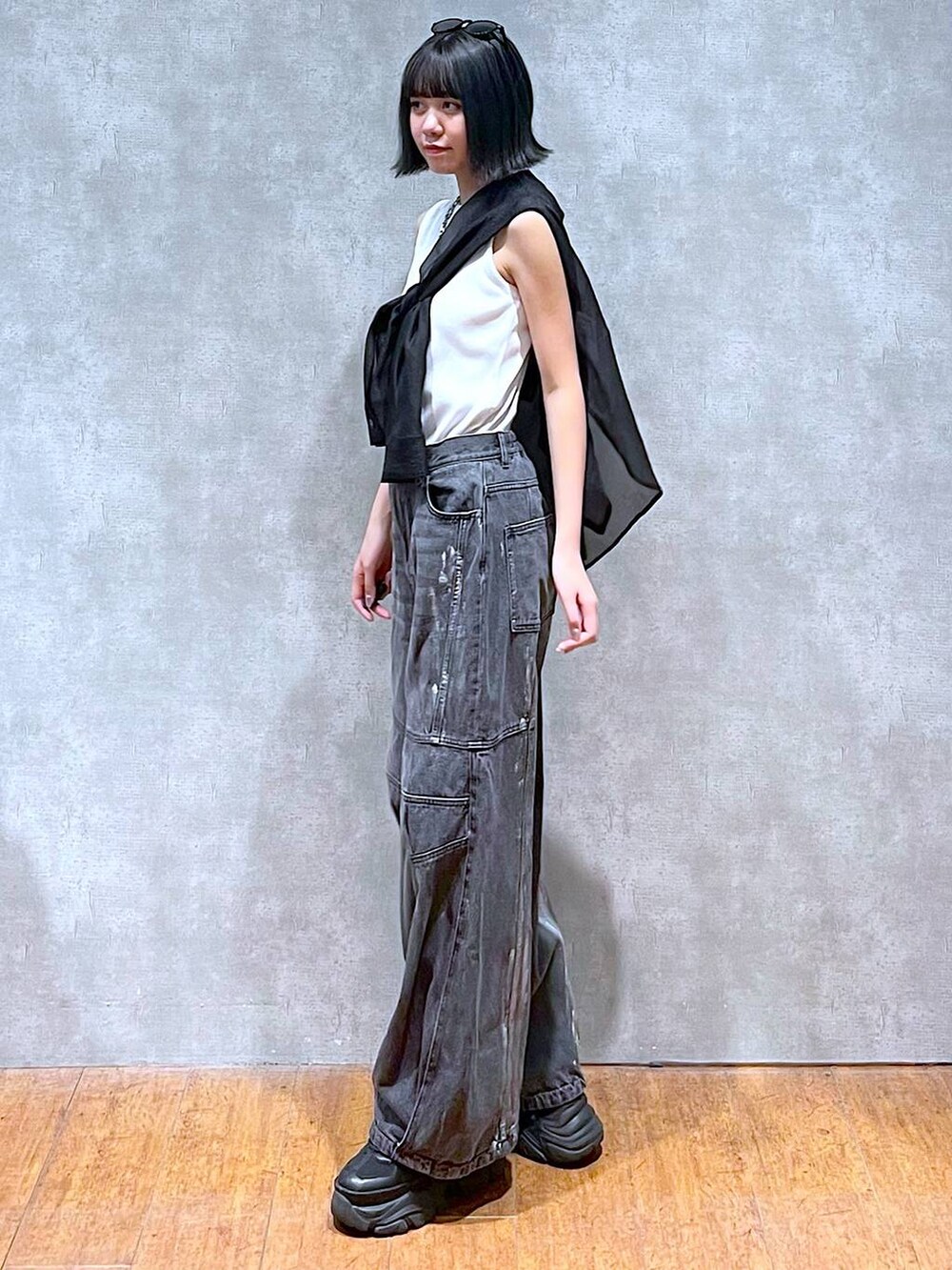 ブラック系のスニーカー、ホワイト系のタンクトップ、ブラック系のデニムパンツを着用したレディースの夏コーディネートの3枚目の写真