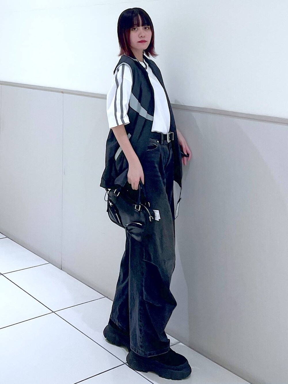 グレー系のベスト、ブラック系のデニムパンツ、ホワイト系のTシャツ/カットソーを着用したレディースの春コーディネートの3枚目の写真