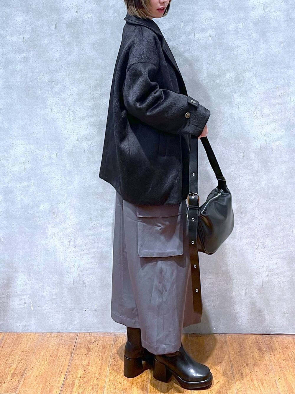 グレー系のスカート、ブラック系のスウェット、ブラック系のショルダーバッグを着用したレディースの冬コーディネートの2枚目の写真