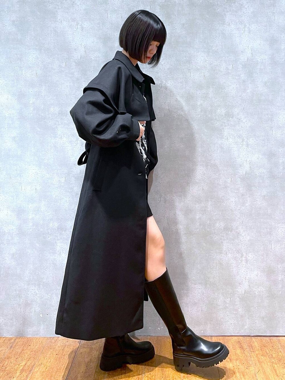 ブラック系のチェスターコート、ブラック系のブーツ、ブラック系のニット/セーターを着用したレディースの冬コーディネートの3枚目の写真