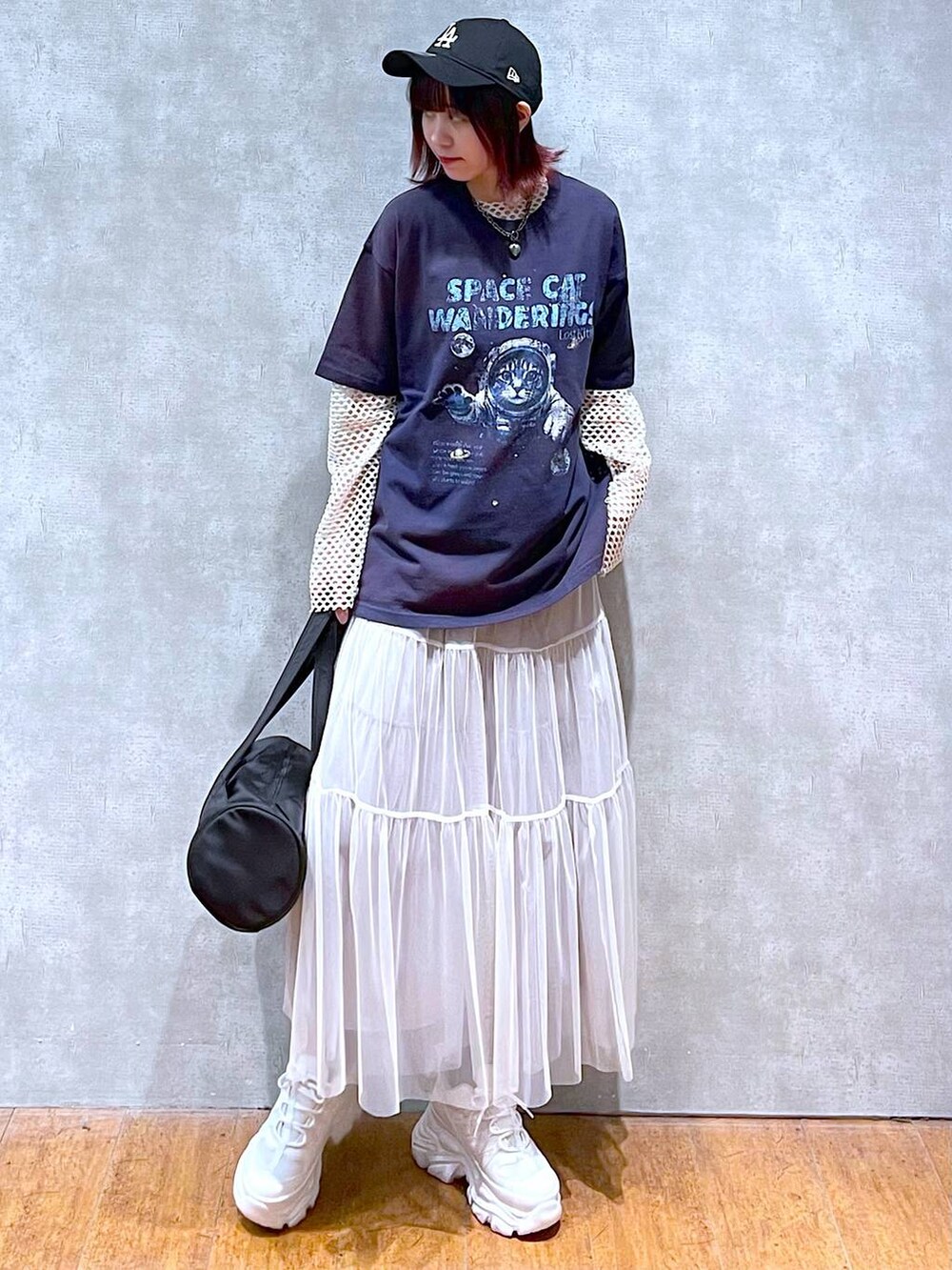 ブラック系のドラムバッグ、ホワイト系のスカート、ホワイト系のスニーカーを着用したレディースの春コーディネートの2枚目の写真