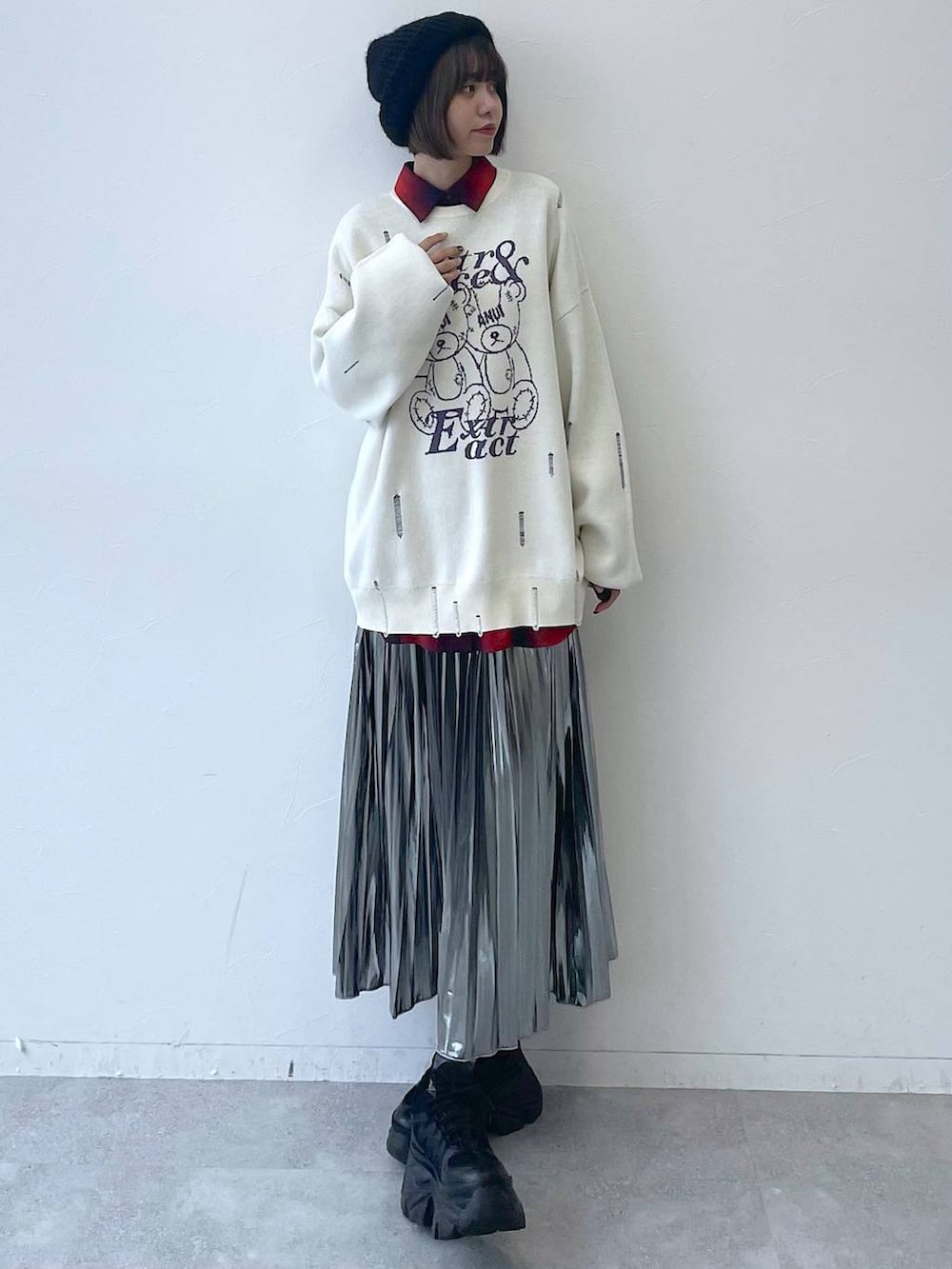 ブラック系のスニーカー、グレー系のスカート、ホワイト系のニット/セーターを着用したレディースの秋コーディネートの3枚目の写真