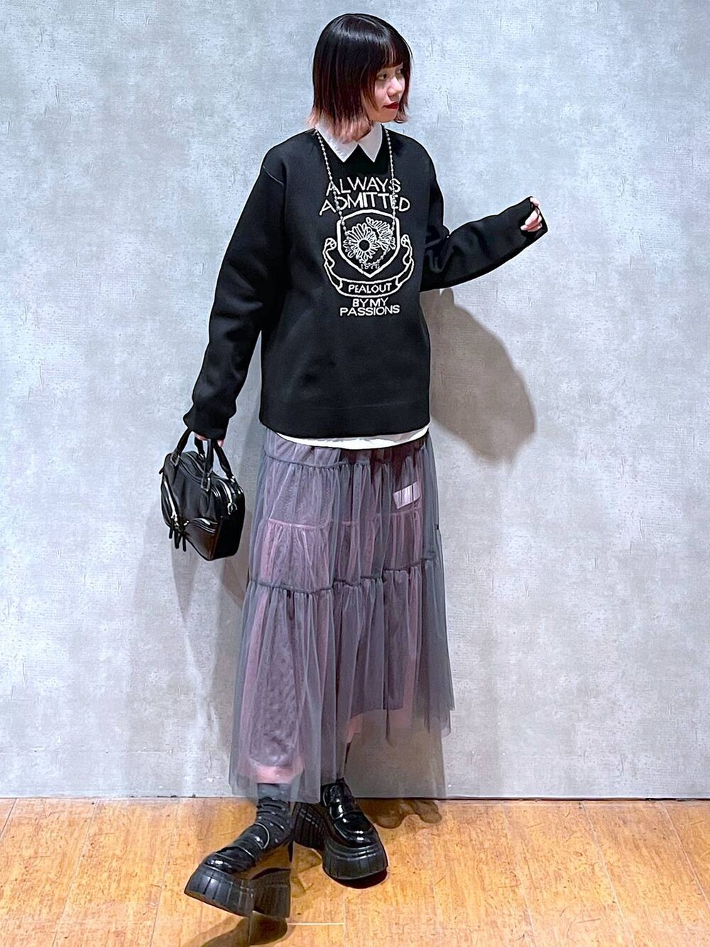 ブラック系のニット/セーター、ホワイト系のシャツ/ブラウス、グレー系のスカートを着用したレディースの春コーディネートの2枚目の写真